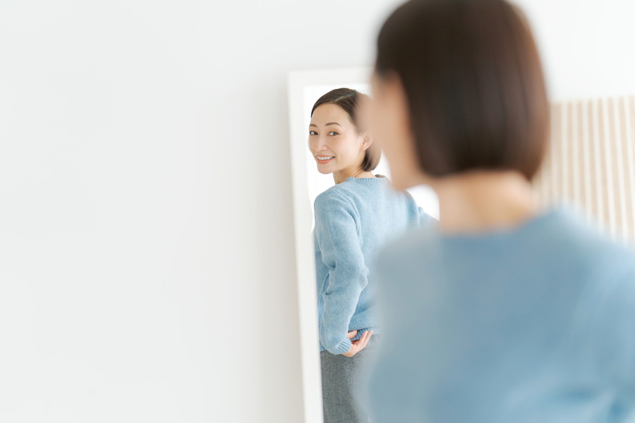 鏡をみて体のラインをみている女性