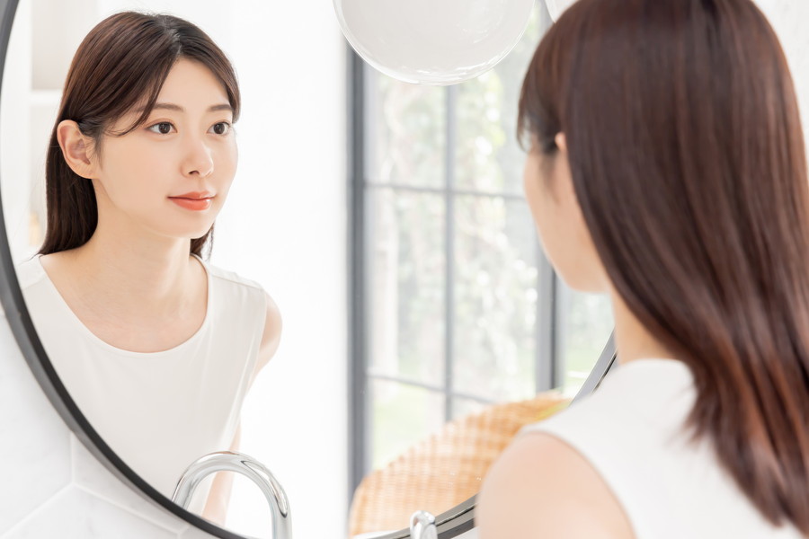 鏡で自分の肌を見ている女性