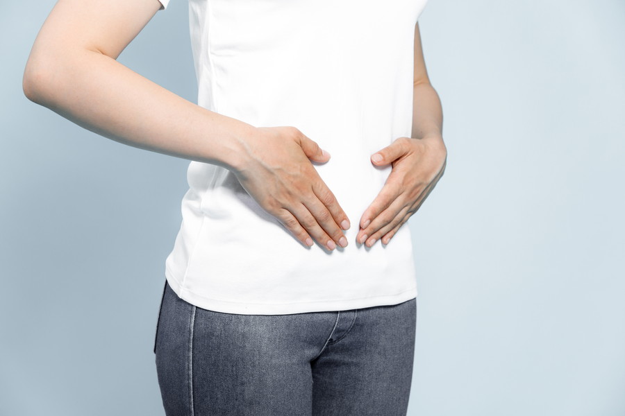 腸を両手で優しくおさえている女性