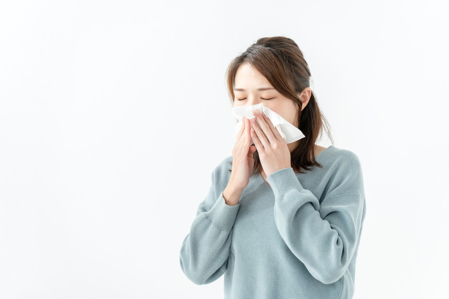 花粉症で鼻をかんでいる女性