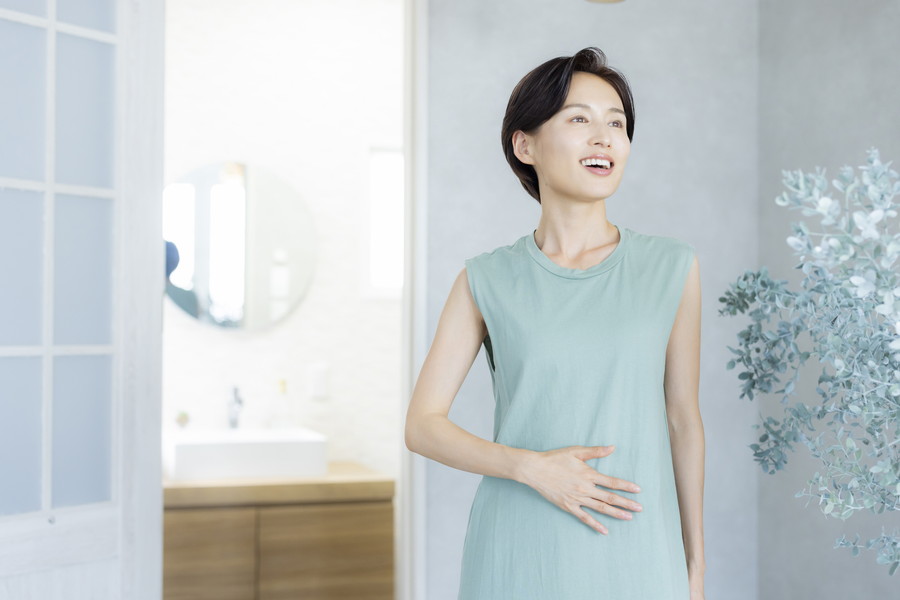 お腹に手をあてて笑顔の女性