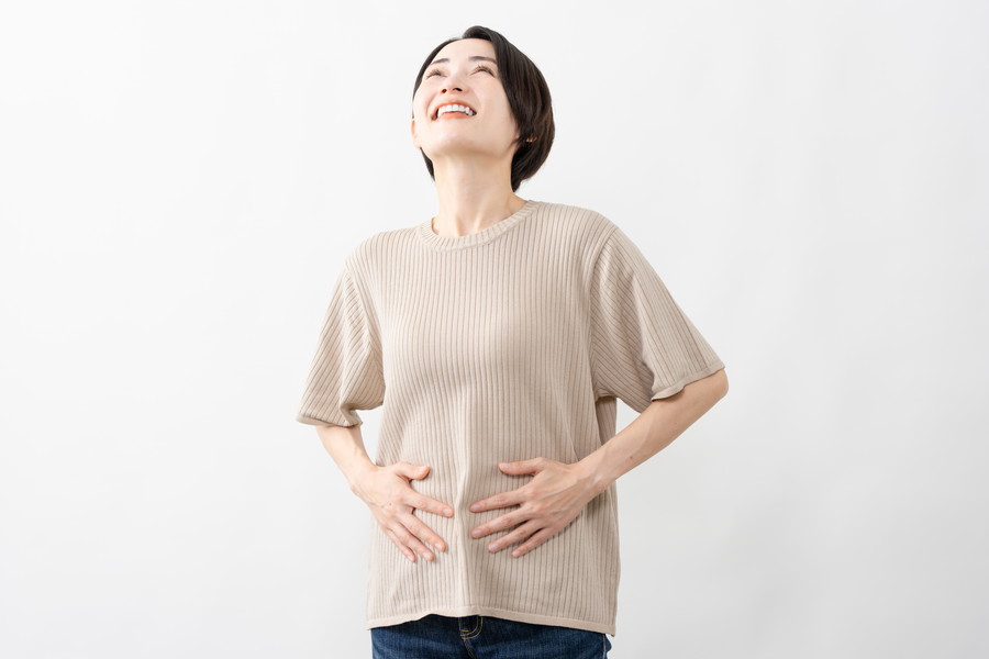 腸に手を当てて笑顔の女性