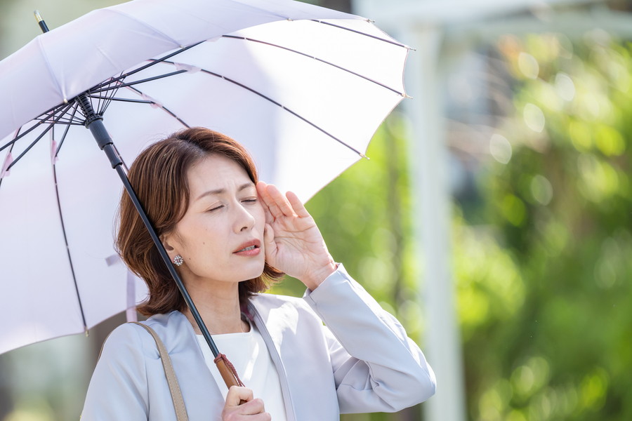 暑くて外で日傘をさしている女性