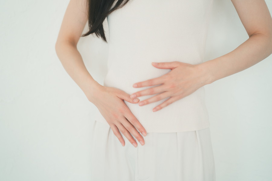 手のひらで腸を抑えている女性